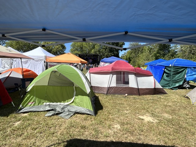 Different color tents are set up at Camp Shaw. There is a stage deep in the background.