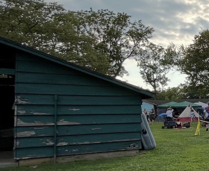 An image of a green cabin at Camp Shaw, showing slightly weather green paint.