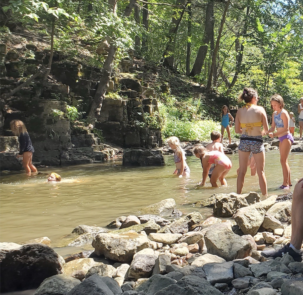 People are playing in Rock Creek and enjoying bubbles next to a stage at Shoe Fest.