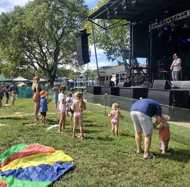 Children enjoying live music with Mr. Dave and watching fire spinners during Shoe Fest’s family activities.