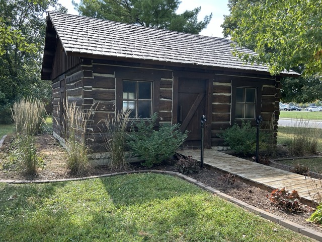 One-room schoolhouse from the 1800s featuring desks and 26-star American flag
