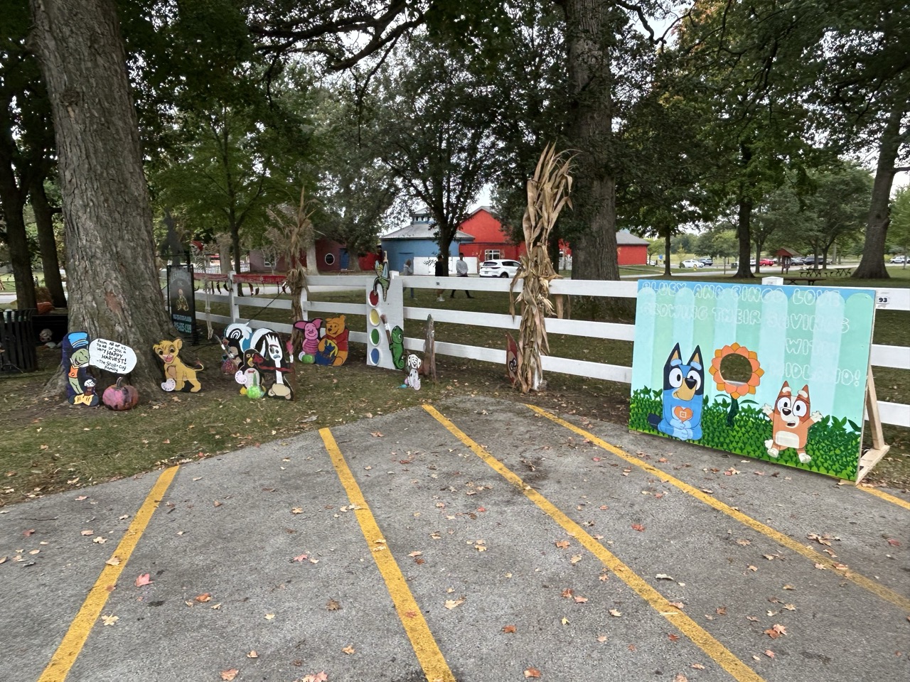 Various themed and traditional scarecrows including Bluey and Bingo, Minions, Hello Kitty, Day of the Dead, a Ghoul Bus, and classic scarecrows.